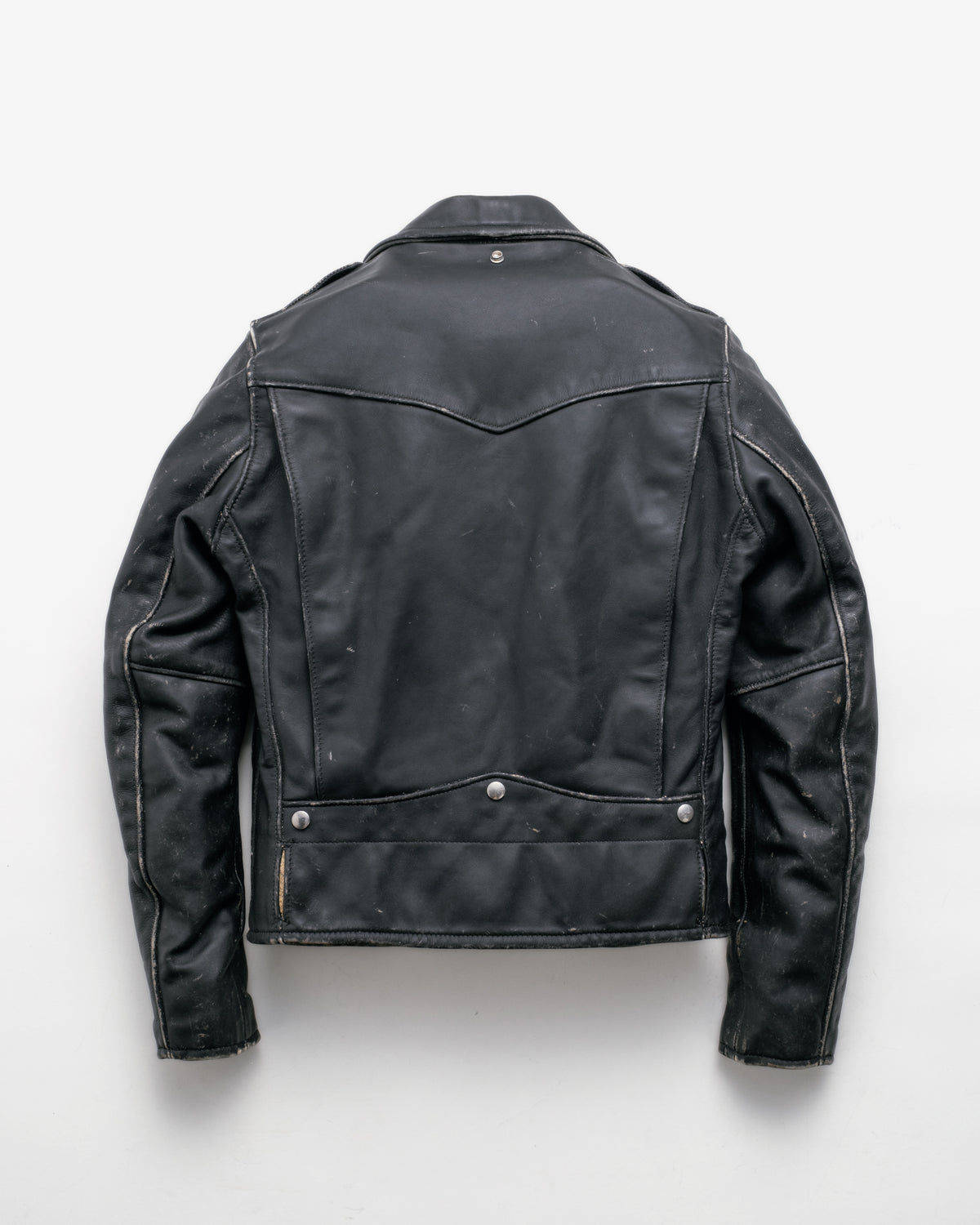 A black leather jacket shown from the back, featuring a collar, shoulder epaulets, and silver snap button details, laid flat against a light gray background.