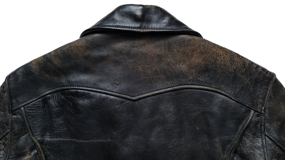 Close-up of the back of a distressed black leather jacket on a white background, showing the weathered texture and classic collar.