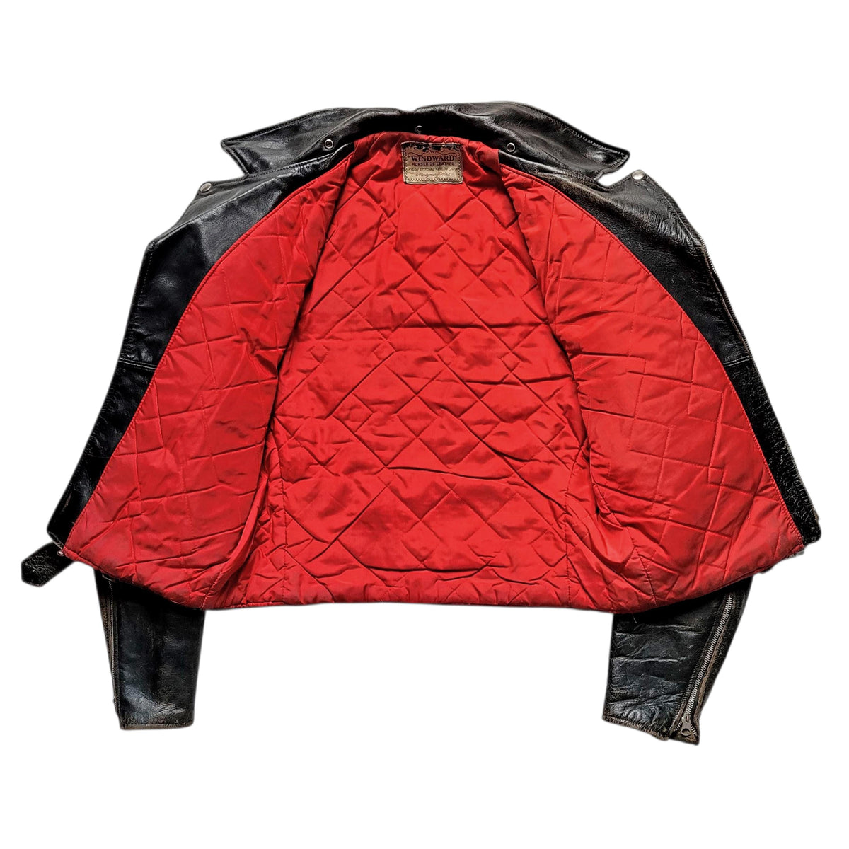 A vintage-style motorcycle jacket with a bright red quilted interior lining and black leather exterior, laid flat against a white background.