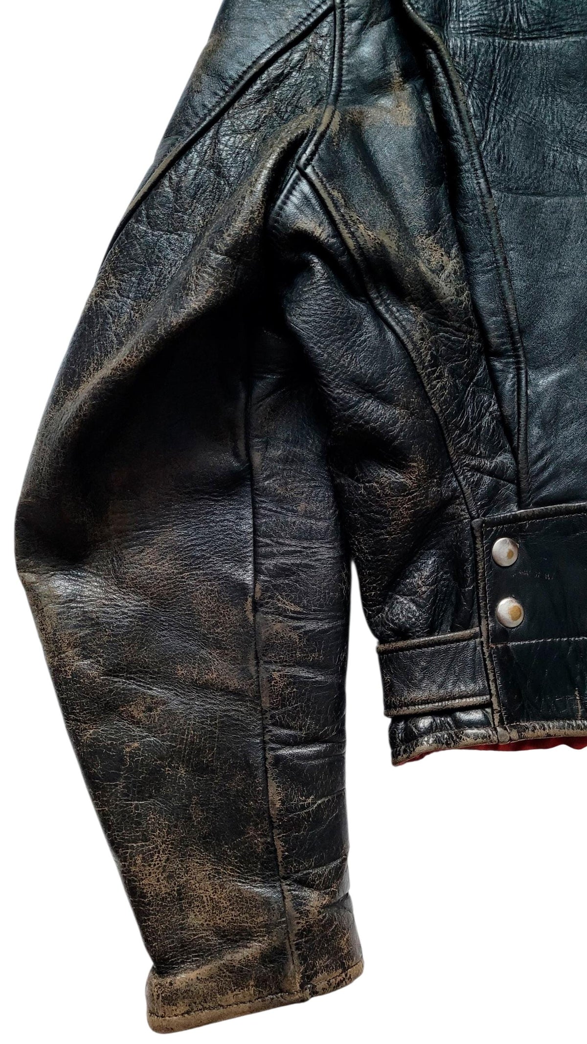 Close-up of a distressed black leather jacket sleeve with silver snap buttons on a white background.