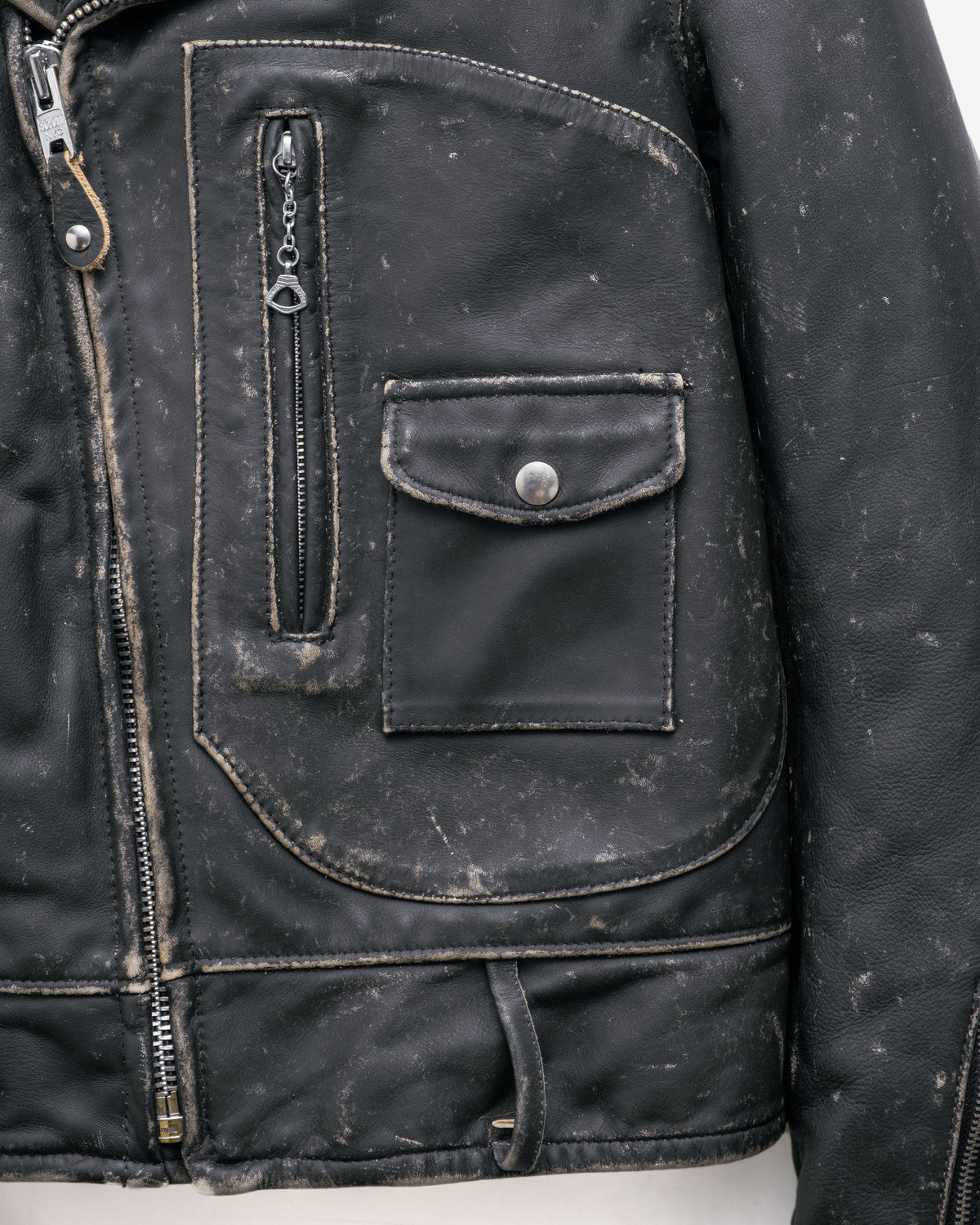 Close-up of a black leather jacket with zipper and pocket details.