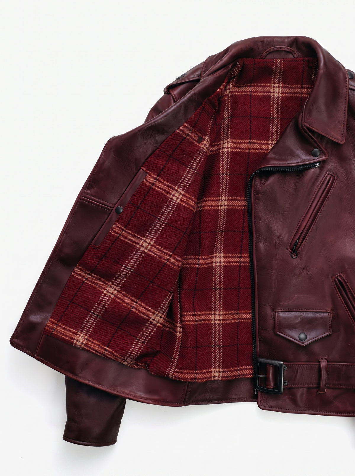 A close-up of a dark burgundy leather jacket with a red and beige plaid lining, displayed against a clean white background.