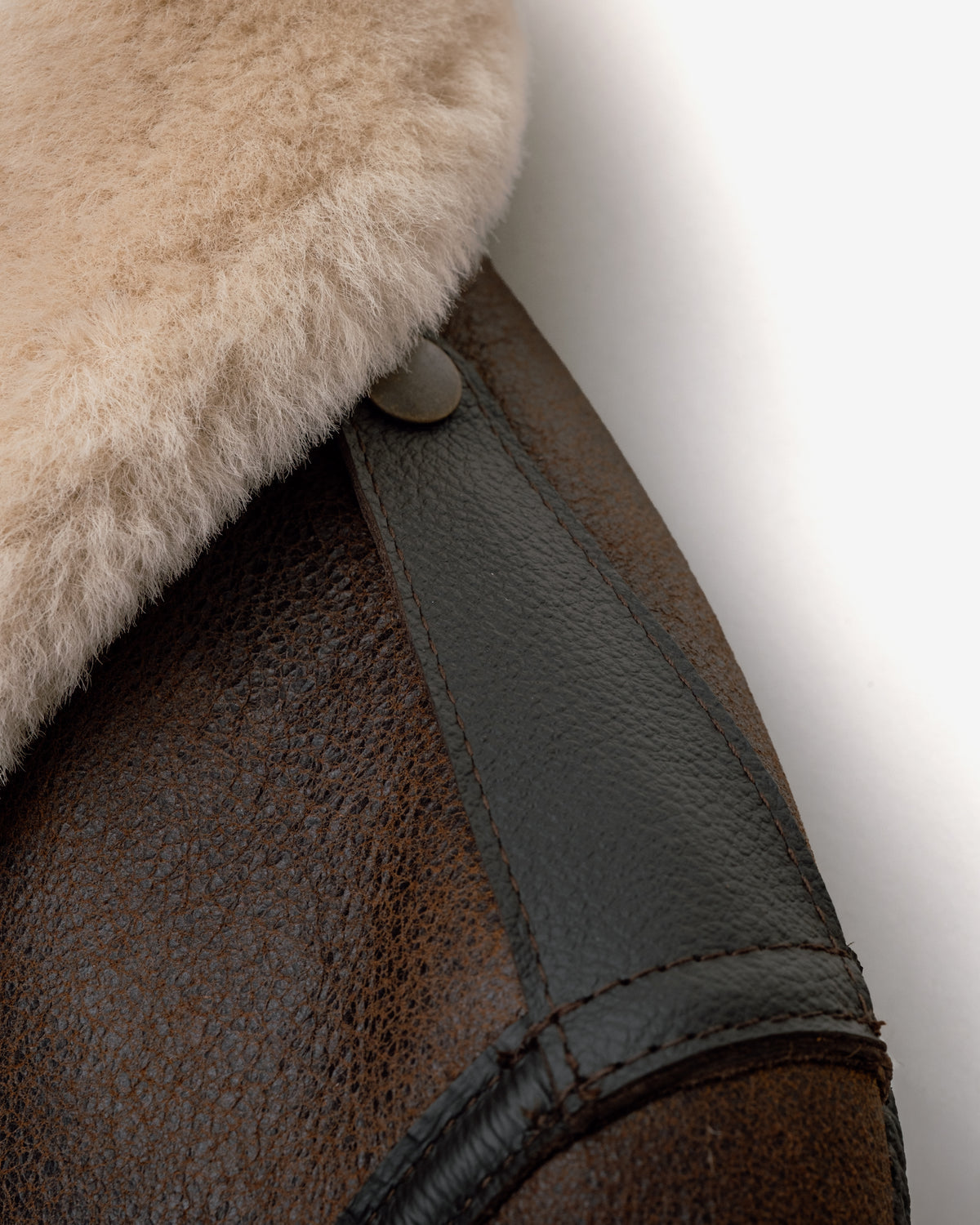 Close-up of a brown leather and fur product with a button on a white background