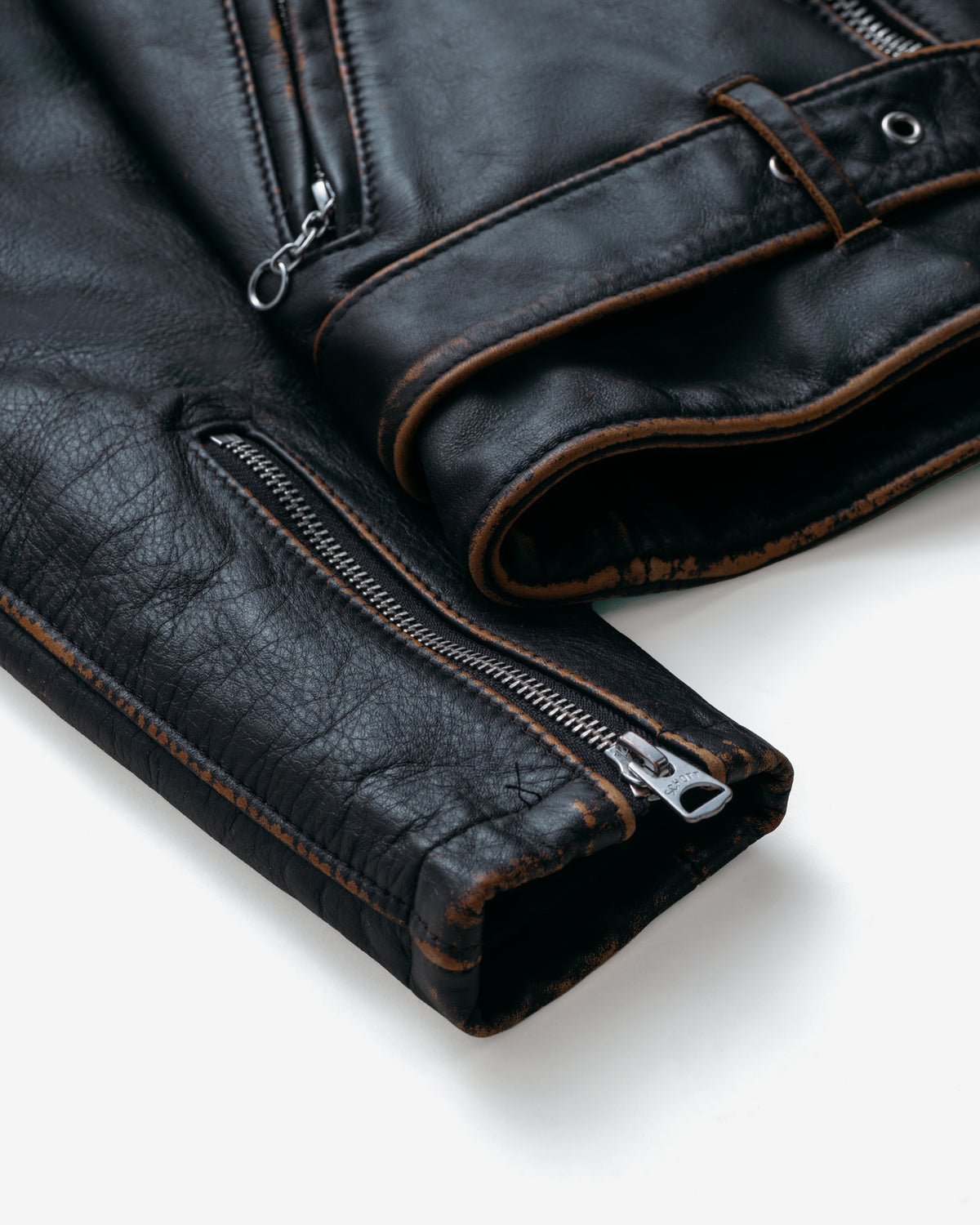 Close-up of a black leather jacket with zipper details on a white background
