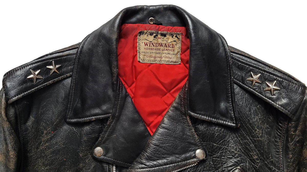 Close-up of a black leather jacket with a red interior lining and a visible Windward label on the collar, shown against a white background.